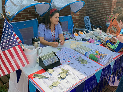 Michelle Sitting at a Table with Origami Money and Coloring Books