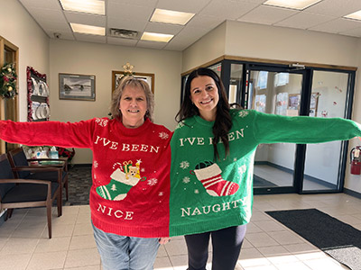 Two women wearing a large, jointed Christmas sweater