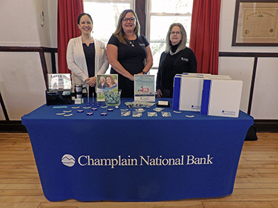 Jackie, Medara, and Valarie standing behind a table with promotional products and brochures