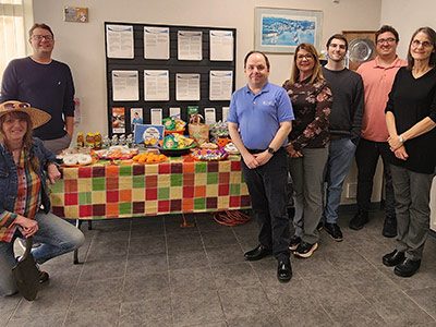 Seven people standing next to a table with decorated for Halloween with food