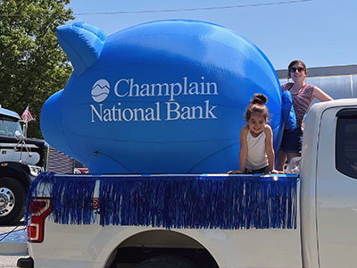 Little girl leaning over side of the cab of a truck with an inflatable piggy bank