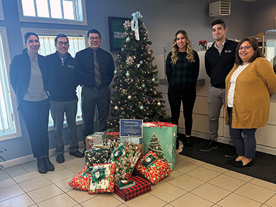 Six People Next to a Christmas Tree with Wrapped Presents